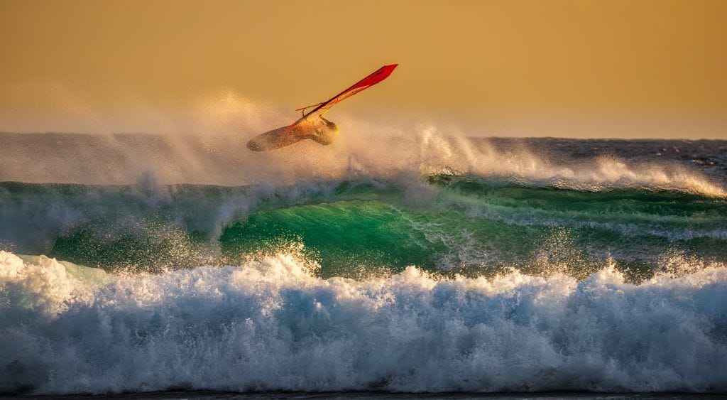 Un chico saltando en una tabla de surf sobre una ola ,representa la decisión que tomamos cuando se iluminan los Rótulos-luminosos